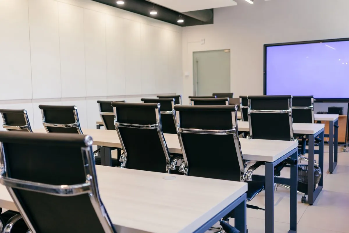 Salle de séminaire moderne équipée de tables, de chaises et d'un écran de projection